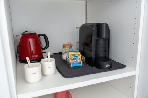 Coffee and tea station with red kettle, black coffee machine, and Tetley tea box in Quarto Minho room at Canhoto Douro