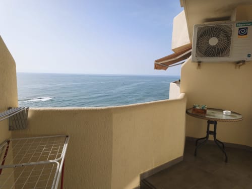 Balcon d'appartement en front de mer avec vue sur la Méditerranée, climatiseur Hisense, petite table et ciel bleu clair à Benalmádena