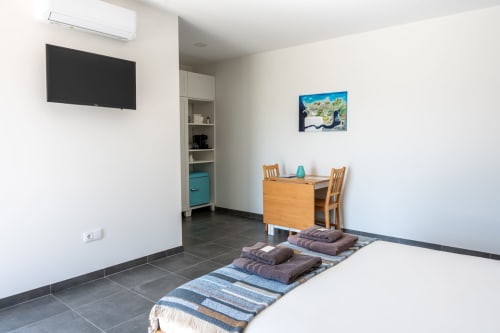 Modern bedroom at Canhoto Douro in São Lourenço do Douro with bed, dining table, wall-mounted TV, and mountain views