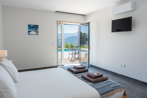 Modern bedroom at Canhoto Douro with pool and mountain views through glass doors, flat-screen TV, and furnished terrace