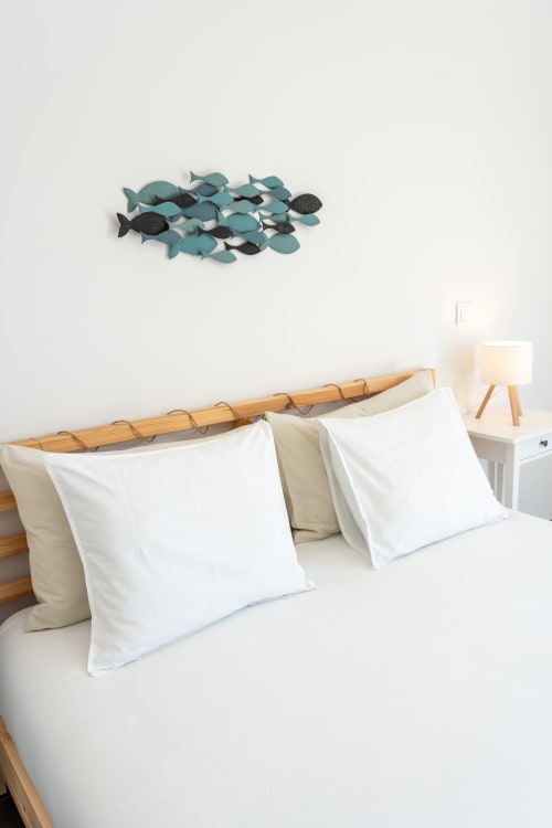 Modern bedroom at Canhoto Douro with white pillows, wooden headboard, and teal fish wall art decoration
