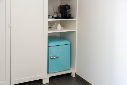 Turquoise Coolbox mini fridge in white cabinet shelving at Canhoto Douro B&B