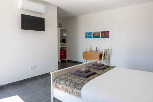 Modern bedroom at Canhoto Douro with bed, work desk, flat-screen TV, and pool view in São Lourenço do Douro