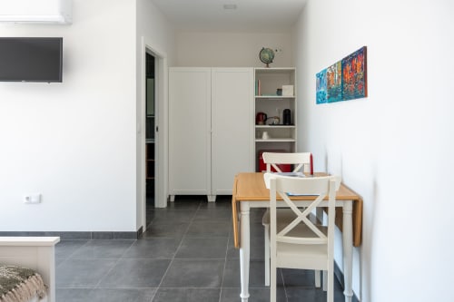 Modern dining area at Canhoto Douro B&B in São Lourenço do Douro with wooden table, white chairs, and mountain views