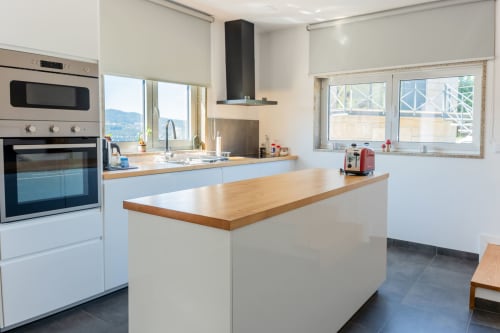 Modern kitchen with wooden island, white cabinetry, and mountain views at Casa da Eira cottage, São Lourenço do Douro