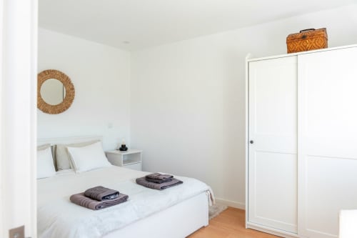Bright bedroom at Casa da Eira cottage in São Lourenço do Douro with queen bed, woven mirror, and white wardrobe