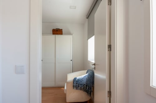 Bedroom at Canhoto Douro cottage with cream armchair, blue throw blanket, white built-in wardrobe, and mountain views from
