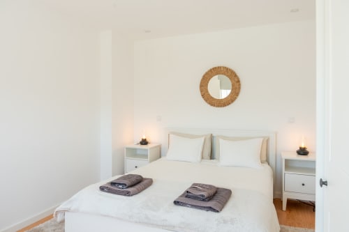 Bright bedroom at Canhoto Douro cottage with white bedding, woven mirror, and mountain views in São Lourenço do Douro