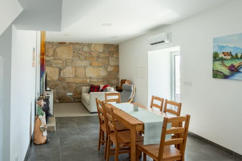 Casa da Eira cottage dining area with wooden table, stone fireplace, and mountain views at Canhoto Douro, São Lourenço do