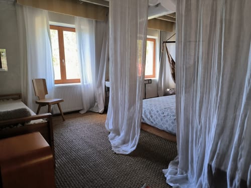 Chambre élégante à la Furanelle B&B à Saint Etienne avec voilages blancs, vue sur les montagnes et décor moderne