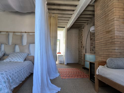 Chambre spacieuse à la Furanelle B&B à Saint Etienne avec lit à baldaquin, poutres apparentes, murs en brique et vue sur les montagnes