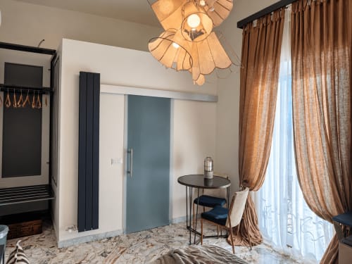 Aletium Signature room at HABITARE Lecce with modern furnishings, blue sliding door, wooden chandelier, and city view balcony