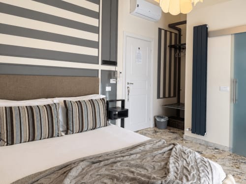 Modern bedroom at HABITARE Lecce with striped headboard, gray and white accents, and city view balcony