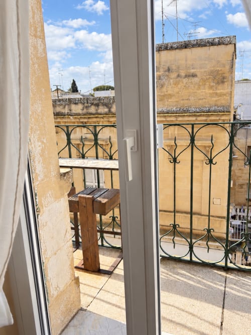 Balcony view from Aletium room at HABITARE Lecce, featuring ornate iron railings and historic honey-colored buildings in