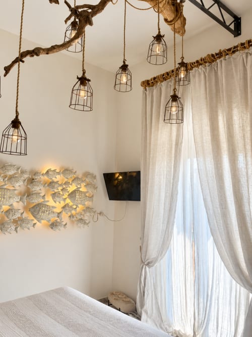 Camera doppia Eco a HABITARE Lecce con lampade a sospensione in rami di legno galleggiante, decorazioni murali a forma di pesce e tende leggere