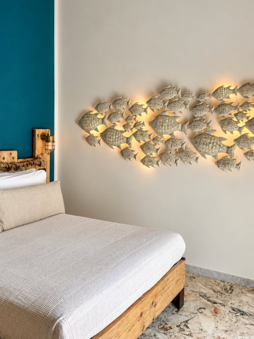 Eco camera doppia HABITARE Lecce: letto in legno, biancheria beige, parete accent turchese e pesce luminoso in metallo