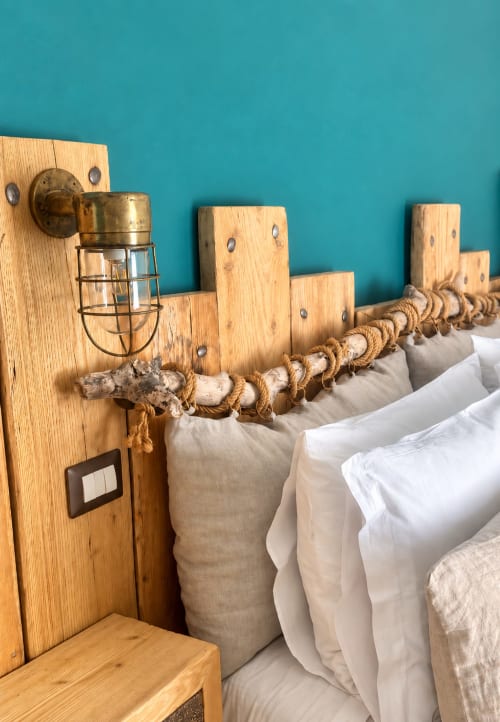 Testiera rustica in legno con dettagli in corda e legno di mare, applique in ottone, muro turchese, cuscini bianchi in boutique hotel a Lecce