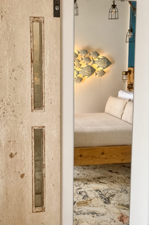 Ingresso della camera Navita presso HABITARE Lecce con letto, cuscini, arte murale con pesci e arredamento d'ispirazione costiera