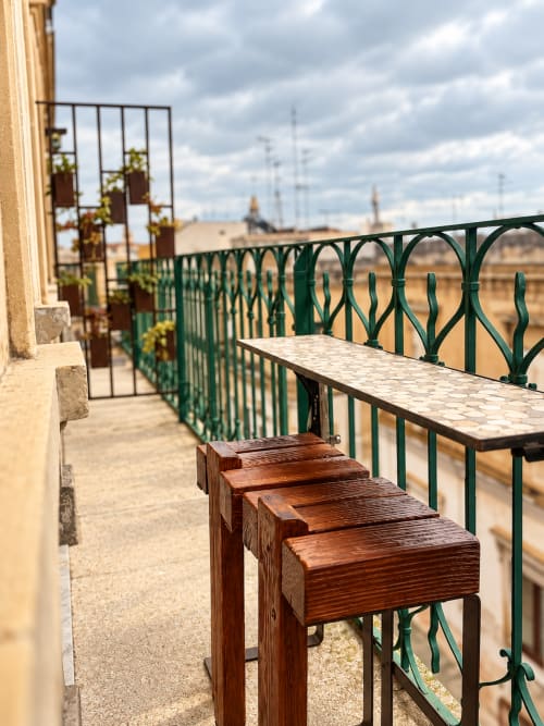 Balcone con sedie in legno e ringhiera in ferro battuto verde che si affaccia sulla campagna di Lecce presso HABITARE Lecce & Salento