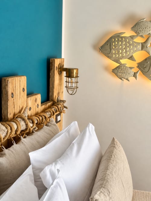 Camera a tema costiero presso HABITARE Lecce con testata in legno avvolta da corde, cuscini bianchi e pesce decorativo in metallo a parete