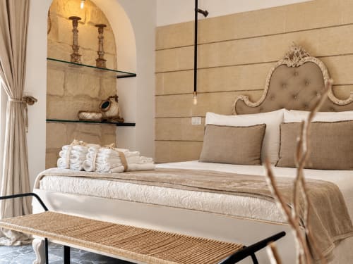 Esclusiva Camera Petra Superior presso HABITARE Lecce con elegante arredamento beige, testata ornamentale e nicchie in alcova