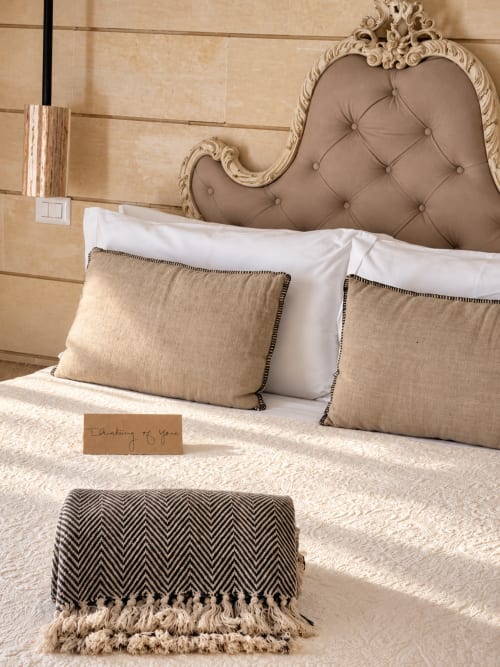 Elegante camera da letto HABITARE Lecce con testata trapuntata, cuscini beige, biancheria bianca e plaid decorativo Petra