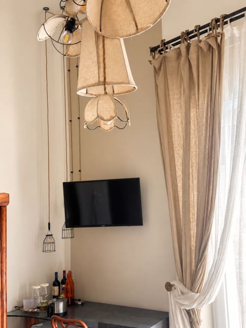 Camera moderna dell'HABITARE Lecce con TV a parete, lampade a sospensione, tende beige e zona di lavoro con minibar