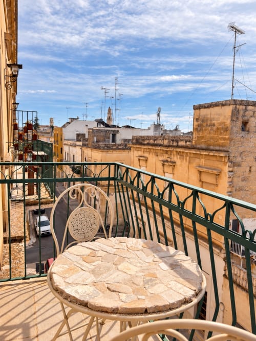 Balcone privato con sedia con vista sui storici edifici in terracotta e i tetti di Lecce, Italia presso l'hotel HABITARE