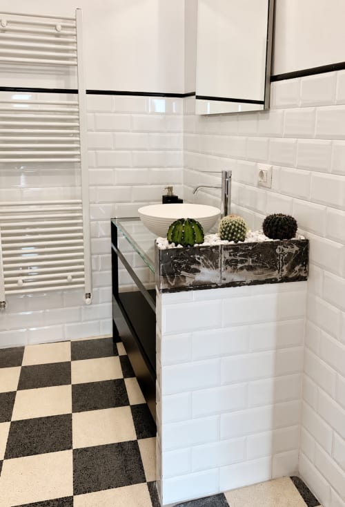 Bagno moderno con piastrelle bianche a metro, dettagli neri, lavabo in marmo e cactus in vaso presso HABITARE Lecce