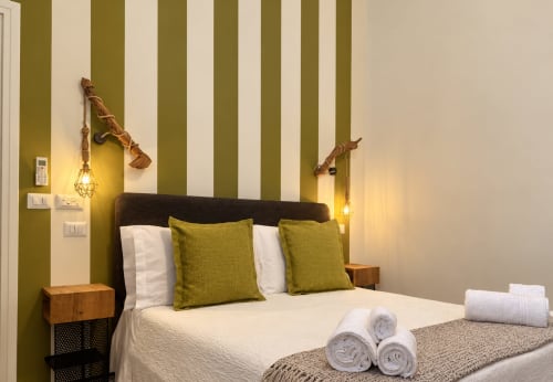 Olivum Standard Double Room at HABITARE Lecce with olive-striped walls, dark headboard, green pillows, and rope pendant