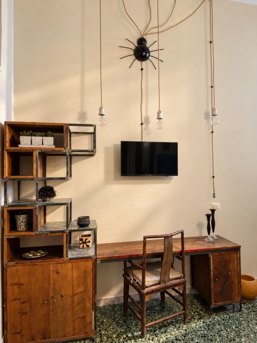 Modern workspace in HABITARE Lecce featuring wood desk, mid-century chair, shelving, pendant lights, and flat-screen TV
