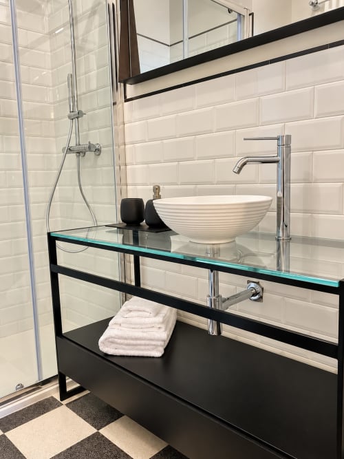 Modern bathroom in Lecce with white subway tiles, black vanity, vessel sink, rainfall shower, and geometric floor at HABITARE