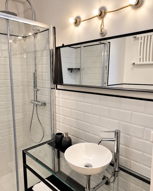 Modern bathroom in HABITARE Lecce with white subway tile, vessel sink, walk-in shower, and vanity mirror with brass lighting