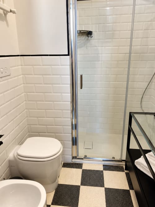 Modern bathroom with white subway tile, toilet, walk-in shower, and checkered floor at HABITARE Lecce hotel