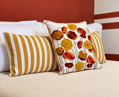 Decorative pillows on bed at HABITARE Lecce hotel with striped and floral patterns in warm tones