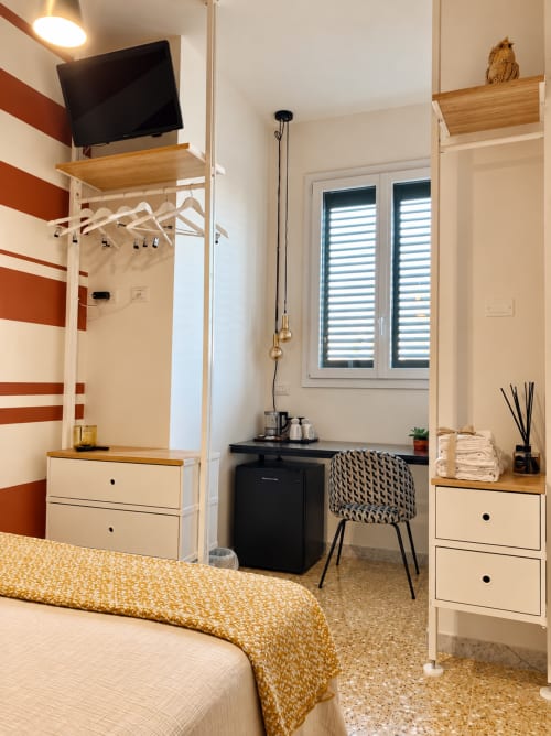 Cozy compact double room at HABITARE Lecce with striped accent wall, work desk, TV, and modern furnishings in Salento