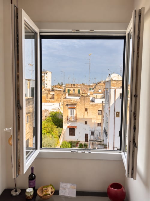 Open window overlooking terracotta rooftops and historic buildings in Lecce, Italy from HABITARE hotel room