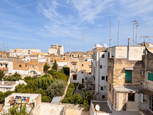 Sunny rooftop view of Lecce's historic terracotta buildings with clotheslines and satellite dishes, showing the charming