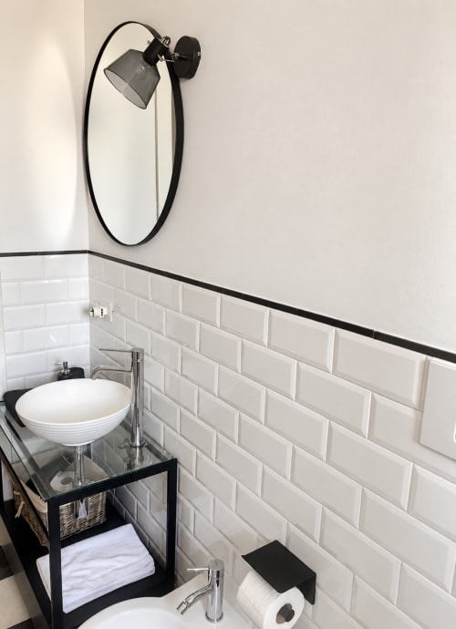 Modern bathroom at HABITARE Lecce with white subway tile, black accent wall, vessel sink, and adjustable wall sconce lamp