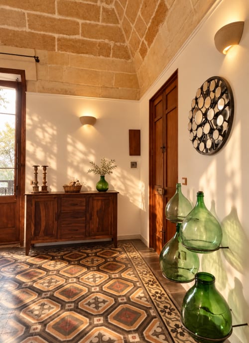 Elegant entryway in HABITARE Lecce apartment with terracotta tile floors, wooden furniture, decorative green bottles, and