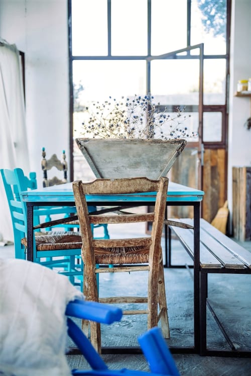Bright dining area at Saveriako Stay with turquoise chairs, wooden table, dried flowers, and sea views through large windows
