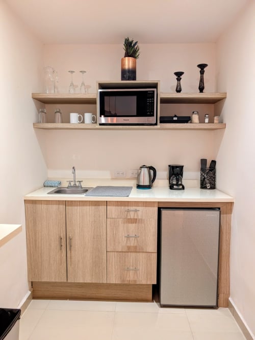 Pequeña cocina moderna en el hotel Casa Donceles de la Ciudad de México con muebles de madera, microondas, minibar y acero inoxidable
