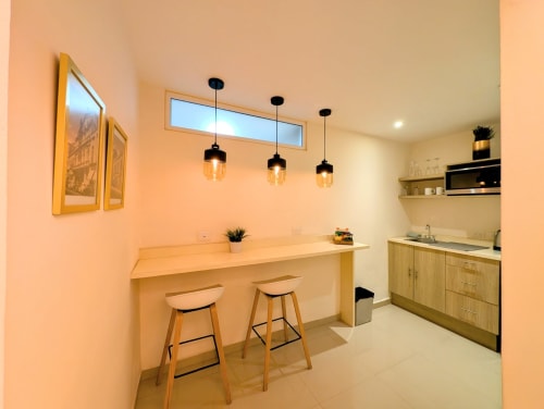 Pequeña cocina moderna en Casa Donceles, estudio de la Ciudad de México con barra, lámparas colgantes y gabinetes de madera