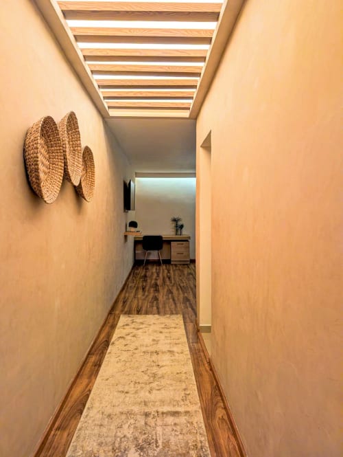 Pasillo del estudio Casa Donceles con vigas de madera, decoración textil en paredes, área de escritorio y piso de madera
