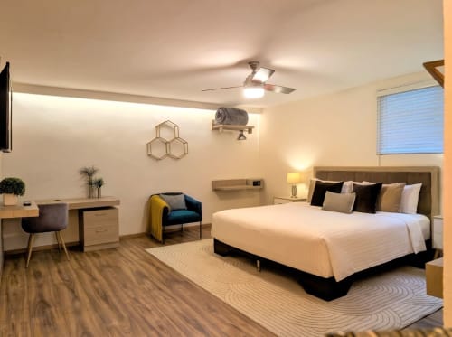 Dormitorio estudio moderno en Casa Donceles, Ciudad de México, con cama king, escritorio, sillón verde azulado, ventilador y madera