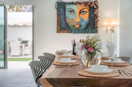 Dining area at Manage Home Tenerife with colorful portrait art, set table with flowers, and pool view in Costa Adeje
