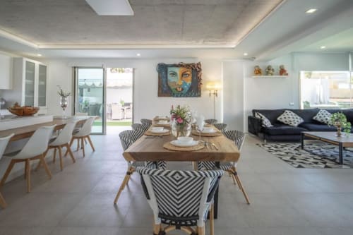 Modern open-plan apartment in Costa Adeje with dining area, black sofa, and pool views through glass doors
