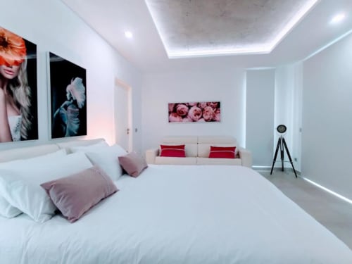 Modern bedroom at Manage Home Tenerife in Costa Adeje with white bed, red accents, and pool view apartment decor