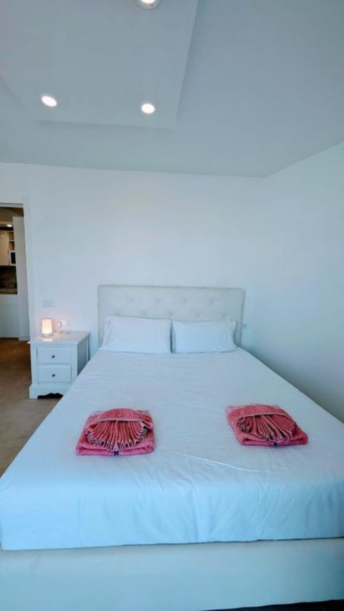 Modern bedroom at Manage Home Tenerife with light blue ceiling, white bed, pink shell decorations, and nightstand in Playa de