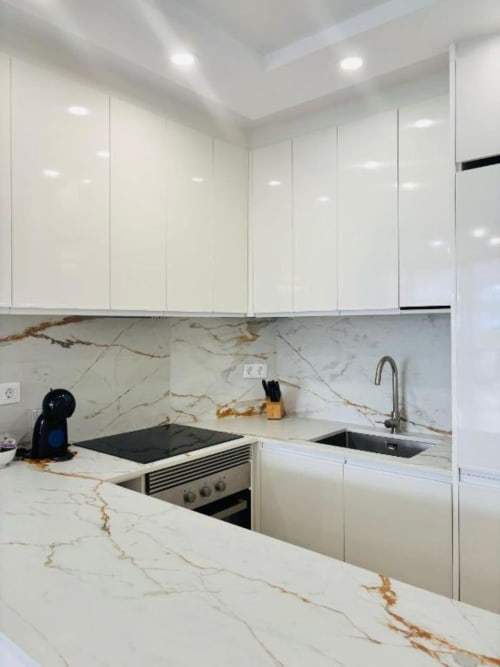 Modern white kitchen with marble countertop and backsplash at Manage Home Tenerife apartment in Playa de las Américas